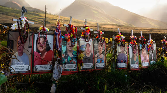 Fotos de fallecidos en los incendios en Hawái bajo cruces blancas en un monumento en memoria de las víctimas de la tragedia de agosto de 2023.